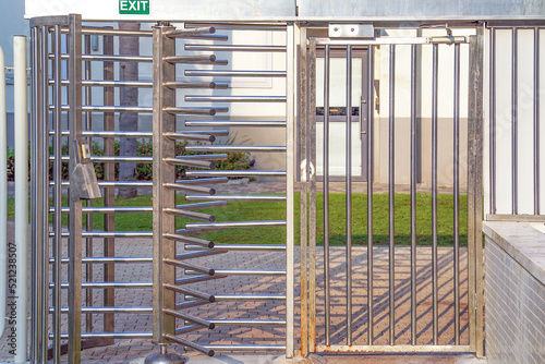 Protected entrance gate - secured turnstiles outdoors. Steel revolving turnstiles at the entrance of production or metro station. Closeup of steel revolving security turnstile on the street photo