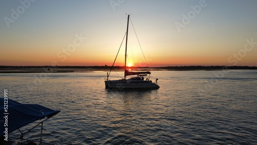 The sun coming through the empy sails of a sailboat photo