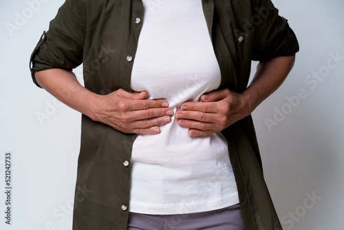 close up. Mature woman having stomach problems experiencing pain in dark green shirt isolated on white background. No face visible middle aged woman with abdominal pain. Healthcare concept.