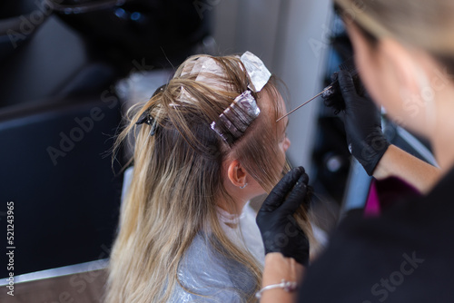 Colorist preparing lock of hair for colouring. photo