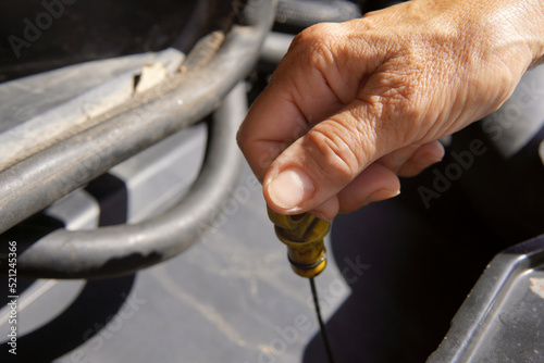 Adult woman checks the level of engine oil in the car.