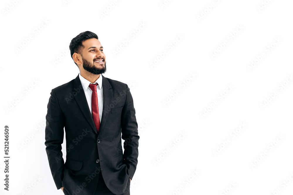 Copy-space for your presentation. Friendly elegant influential arabian or indian man in formal suit, standing over isolated white background, looking away, thinking, planning, dreaming, smiles happily Copy-space for your presentation. Friendly elegant influential arabian or indian man in formal suit, standing over isolated white background, looking away, thinking, planning, dreaming, smiles happily