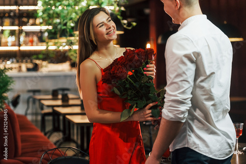 Man gives flowers. Romantic couple have dinner in the restaurant