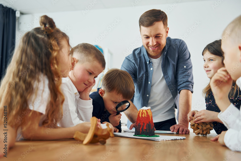Looking at the model of volcano. Group of children students in class at school with teacher Looking at the model of volcano. Group of children students in class at school with teacher