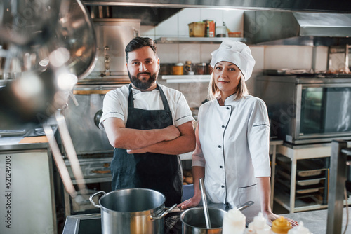 Man and woman standing and posing. Professional chef preparing food in the kitchen