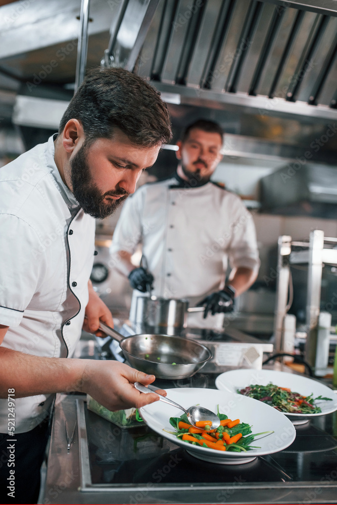 Two brothers is making salad. Professional chef preparing food in the kitchen Two brothers is making salad. Professional chef preparing food in the kitchen