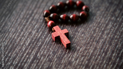 Wooden cross, rosary on wooden background. Symbol of Christianity and faith. Prayer. Concept Palm Sunday, Good Friday, Easter. Selective focus. Copy cpase. Close-up photo