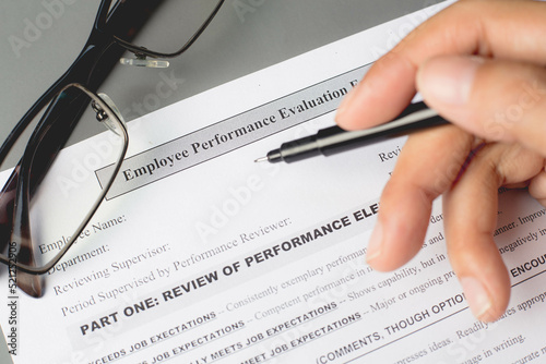 Close-up of a business person filling out an employee performance appraisal form.