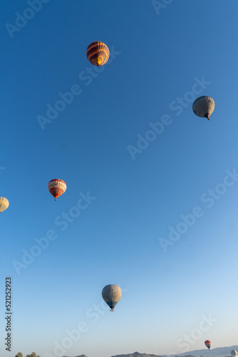 Landscape of the Valley of Love in Cappadocia, at dawn, with hot air balloons flying.