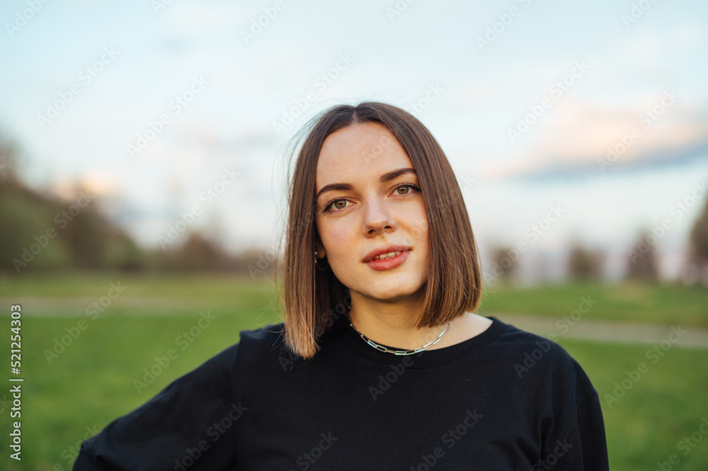 Close-up portrait of attractive woman in dark clothes outdoors on weekend, posing for camera. Close-up portrait of attractive woman in dark clothes outdoors on weekend, posing for camera.