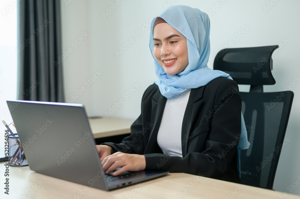 Young muslim business woman working on laptop with documents in modern office Young muslim business woman working on laptop with documents in modern office