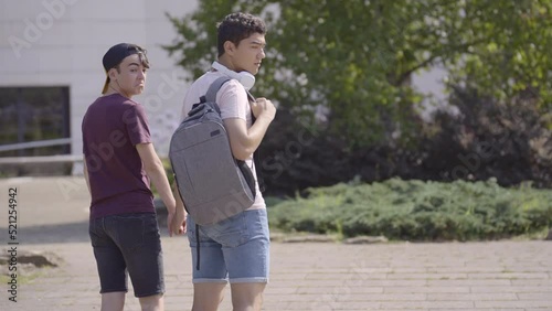 Homophobic teenager girl insulting and making fun of gay couple. Students walking holding hands in a park.
