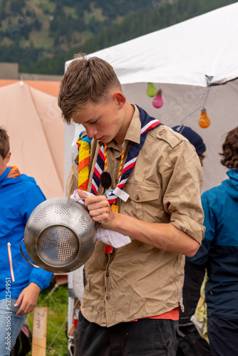 Boy scout cleaning kitchenware in a campsite photo
