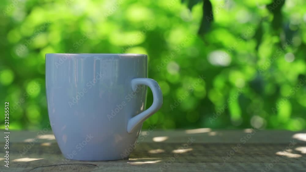 Hot drink in a cup against the background of a summer garden in the morning Hot drink in a cup against the background of a summer garden in the morning