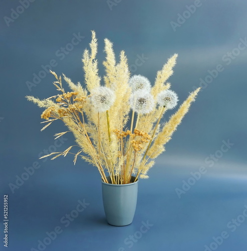  Natural  bouquet with dry branches and pampas in vase on table. Still life with dandelions  on a gray background. For decorations at home fall and winter.