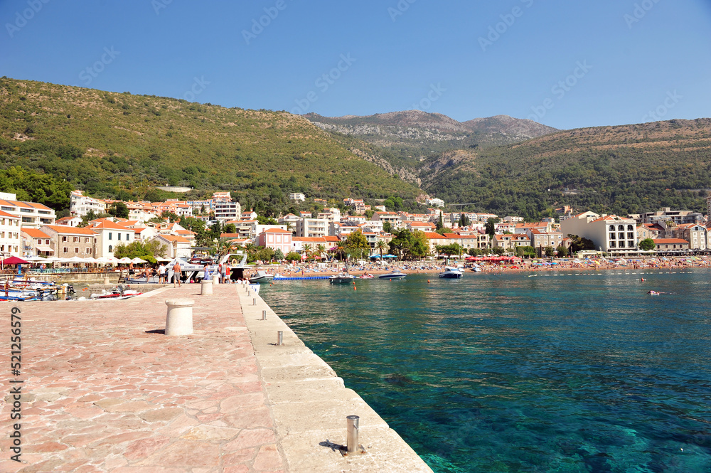 View from pier towards little idyllic village Petrovac in Montenegro.  Clear summer day and turquoise blue ocean.
