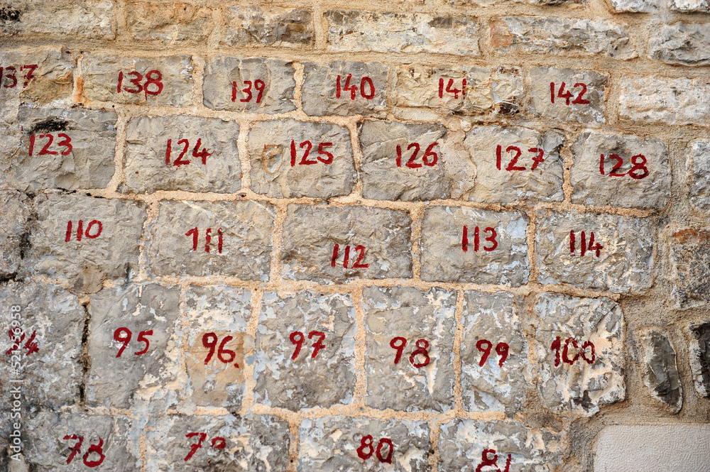 Close up of brick wall with numbered bricks in old town, Budva, Montenegro. Red numbers on old bricks.