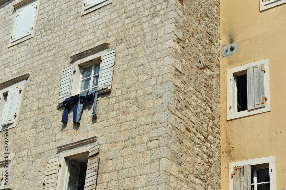 Old brick building in Budva, Montenegro. Jeans hanging out of window to dry in the sun.  Horizontal photo taken from low angle.