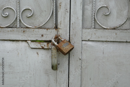 Old rusty iron lock on gray metal gates.