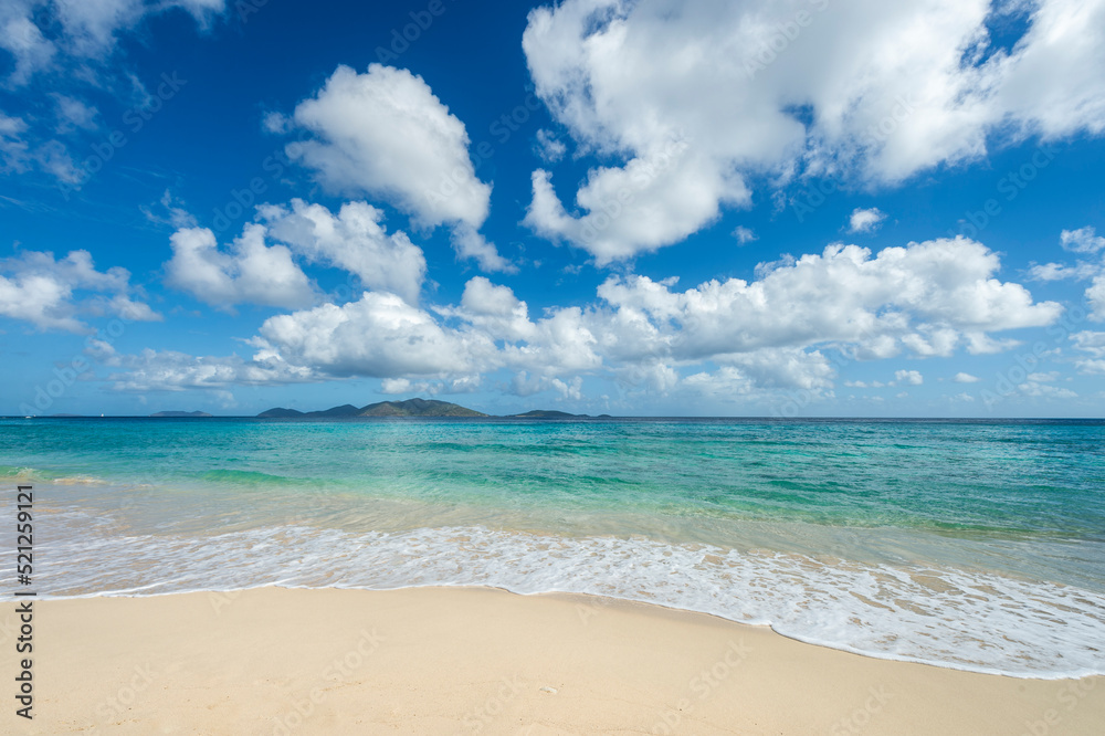 Jost Van Dyke viewed across turquoise Caribbean waters from the white sands of Apple Bay Beach on Tortola, BVI 