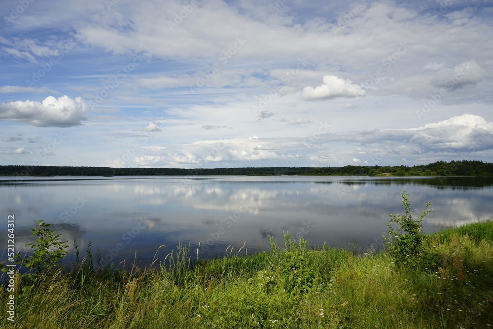 White clouds and reflection in the lake. Open spaces. Horizon. Summer	