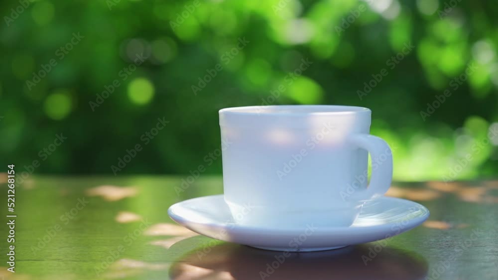 Hot drink in a cup against the background of a summer garden in the morning Hot drink in a cup against the background of a summer garden in the morning