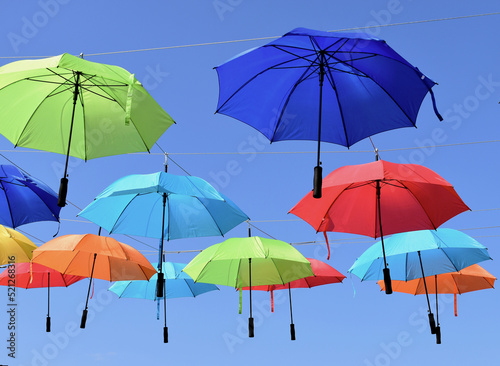 colorful parasols. sun protection umbrellas suspended from overhead steel wires. travel  tourism and vacation theme. climate change and global warming concept. design and urban environment. 