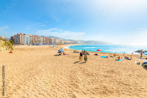 The wide sandy beach at the Costa Brava resort town of Lloret de Mar  Spain  as the fog breaks and local Spaniards and tourists enjoy the blue Mediterranean sea.