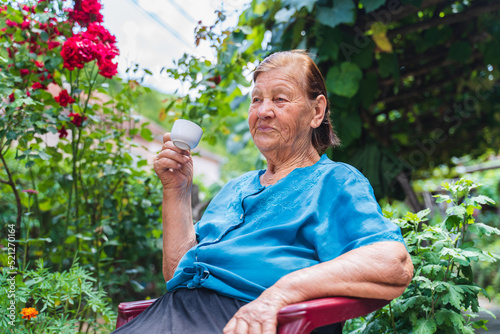 Grandma drinking coffee outside in her house garden during the day