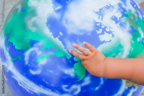 Fototapeta Naklejka Na Ścianę i Meble -  A child's hand on a large model of the planet earth