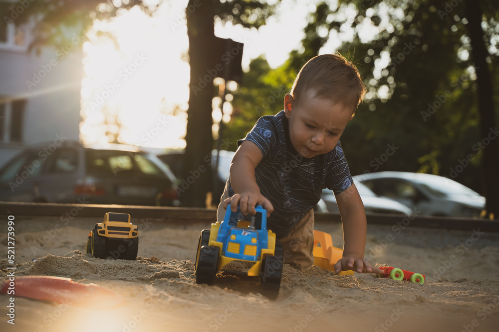 Kid playing with toys in sandbox. Little boy having fun on playground in sandpit. Outdoor creative activities for kids. Summer and childhood concept Kid playing with toys in sandbox. Little boy having fun on playground in sandpit. Outdoor creative activities for kids. Summer and childhood concept