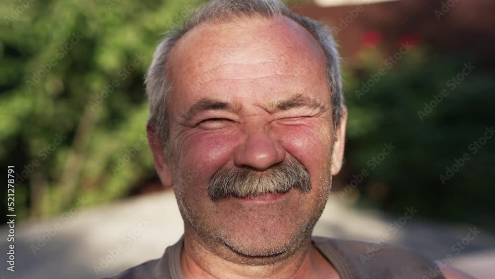 Happy elderly man squinting at the sun Happy elderly man squinting at the sun