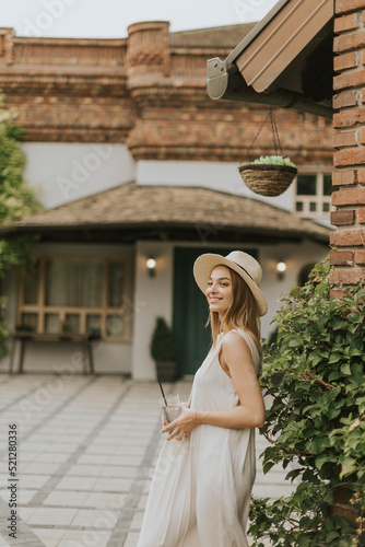 Young woman with hat drinki...