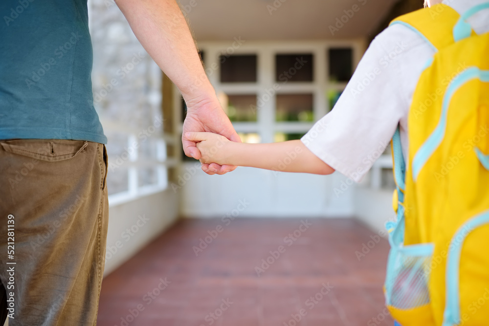 Little schoolboy with his father goes to school after summer holiday. Parent accompanies the child. Education for children. Kids back to school concept. Little schoolboy with his father goes to school after summer holiday. Parent accompanies the child. Education for children. Kids back to school concept.