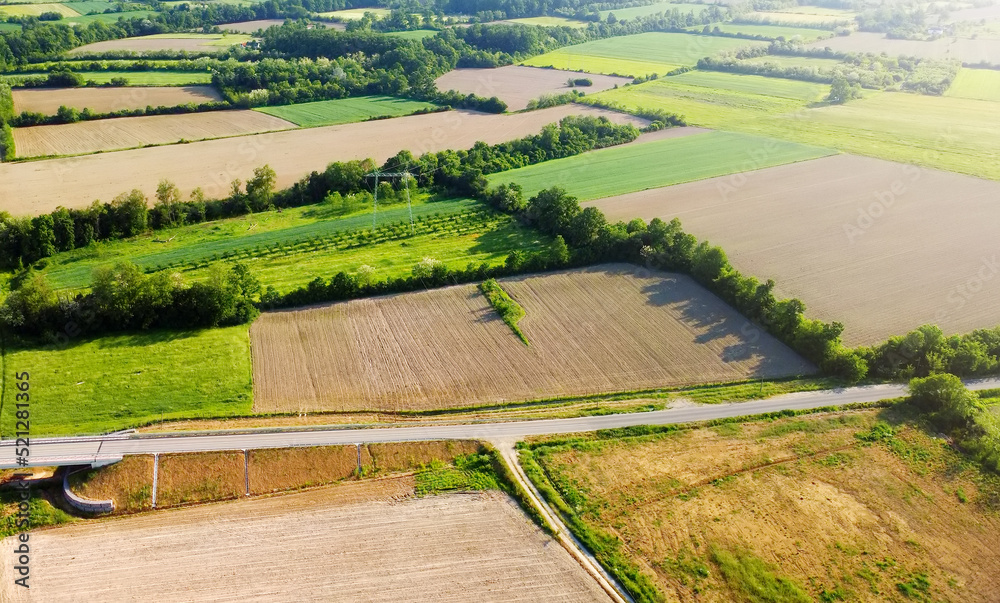 Aerial european countryside landscape at sunset. Drone point view of agricultural fields, roads, copses.