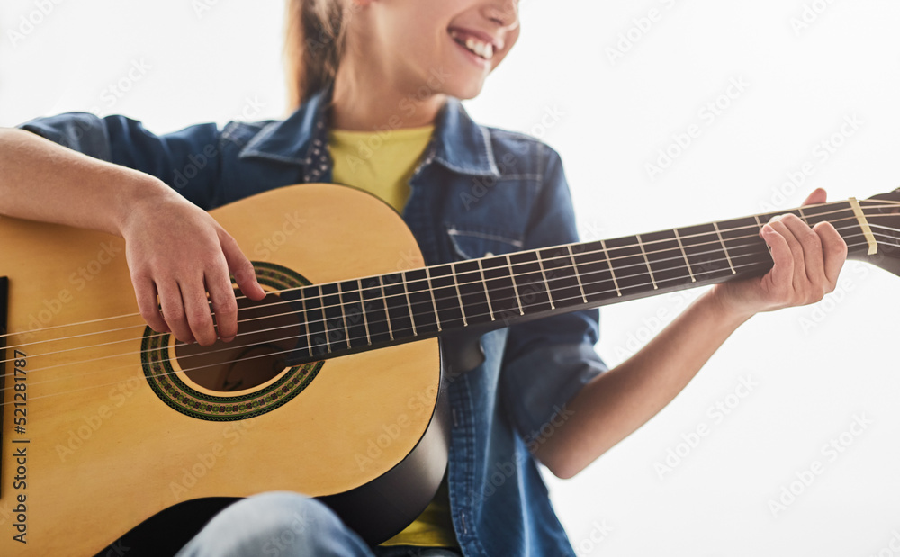 Gleeful teenager playing guitar during lesson Gleeful teenager playing guitar during lesson
