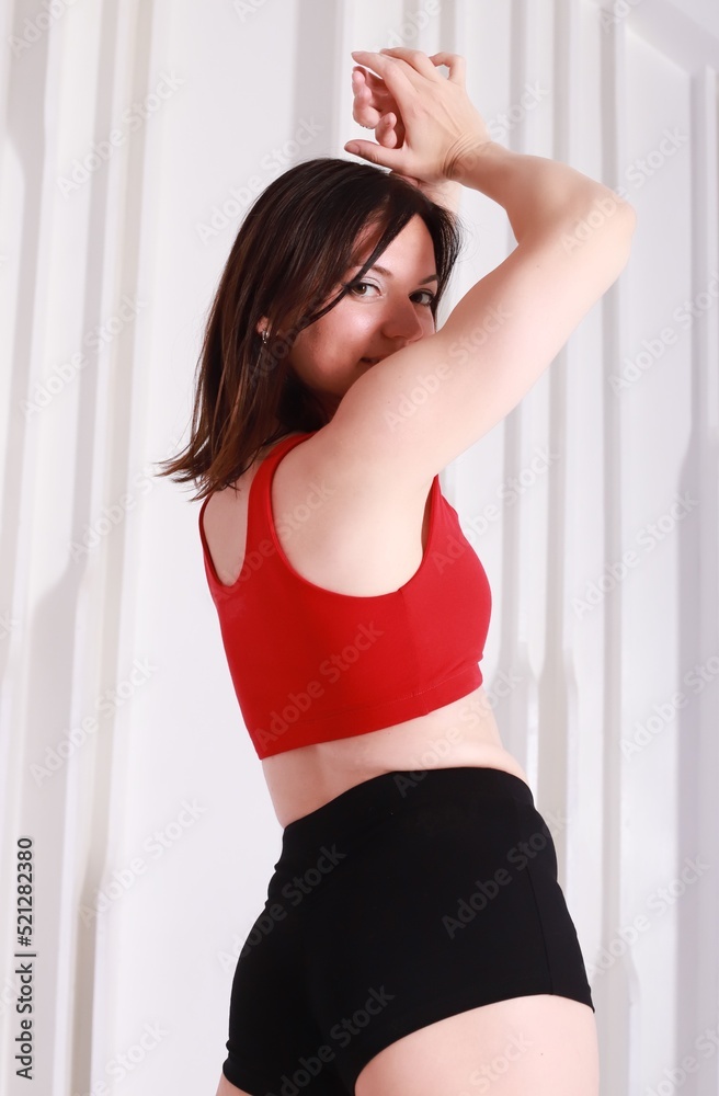 A beautiful brunette in red sportswear posing in a white studio