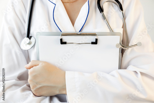 A woman doctor in a white coat holds a clipboard in her hands. Close-up photo.