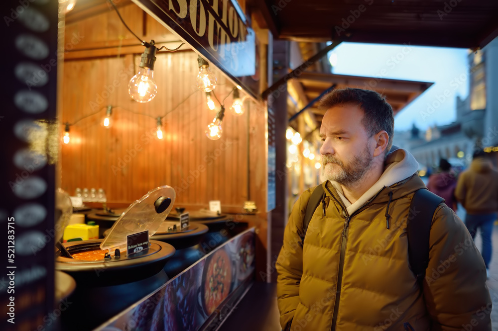 Mature man buying street food on european Christmas market. Hot soup is a traditional local cuisine in winter season