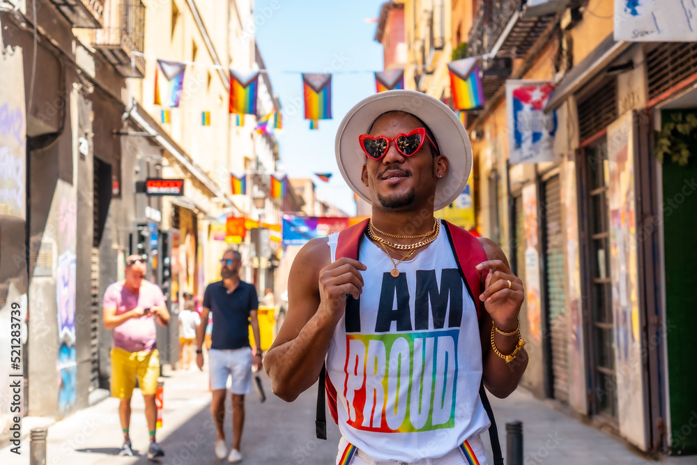 A tourist man of gay black ethnicity enjoying and smiling at the pride party, LGBT flag