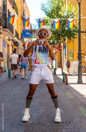 Portrait of a gay black man at the pride party taking photos, LGBT flag