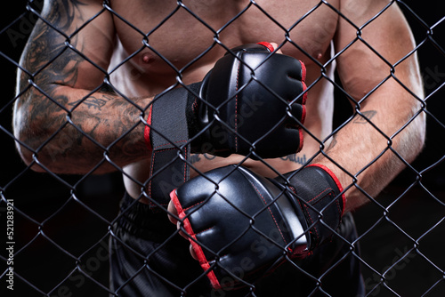 Professional kickboxing fighter puts on gloves in a cage ring. The concept of sports, Muay Thai, martial arts.