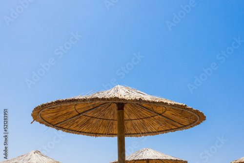 Fototapeta Naklejka Na Ścianę i Meble -  Bamboo parasols beach umbrellas with clear blue sky background on summer day
