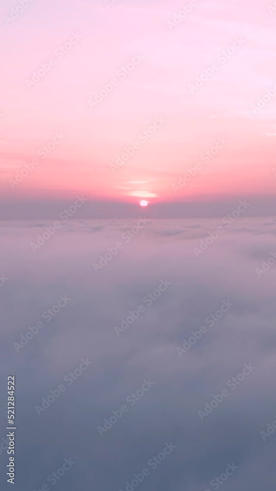 Aerial vertical shot of clouds with pink sunset on top