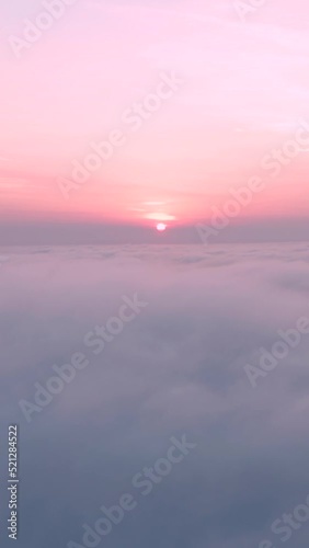 Aerial vertical shot of clouds with pink sunset on top