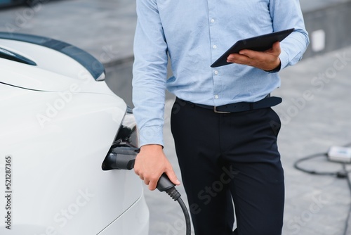 a businessman charges an electric car.