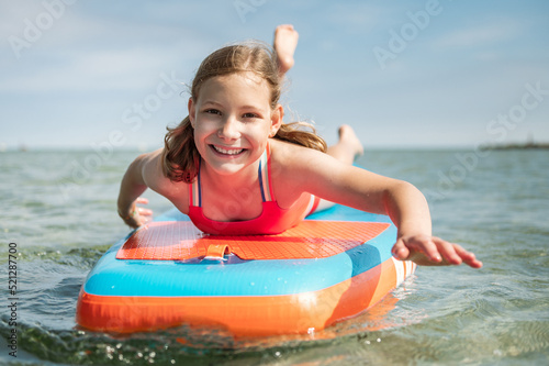 Happy teen girl lying on SUP board and enjoy water
