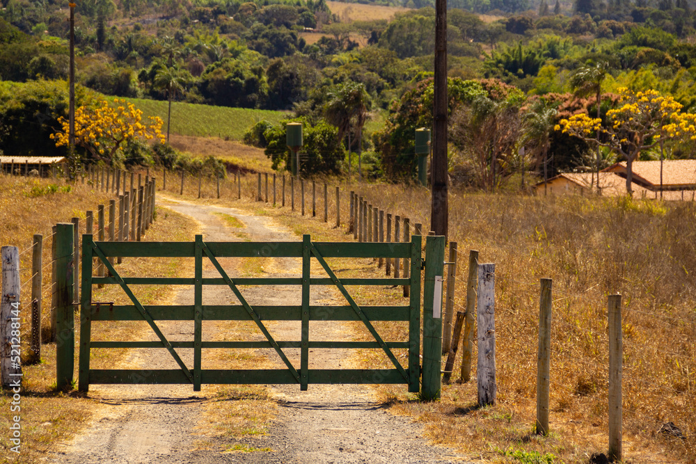 Uma porteira de madeira pintada de verde na entrada de uma fazenda. Paisagem de beira de rodovia em Goiás. Uma porteira de madeira pintada de verde na entrada de uma fazenda. Paisagem de beira de rodovia em Goiás.