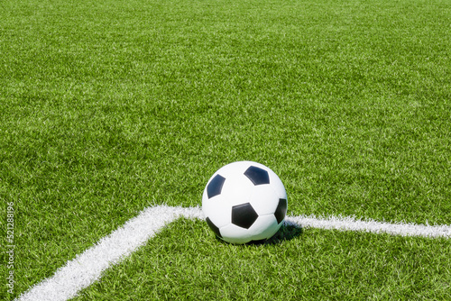 Soccer ball on green synthetic artificial grass soccer sports field with white corner stripe line