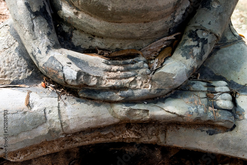 Close-up of o broken statue of Buddha in lotus pose